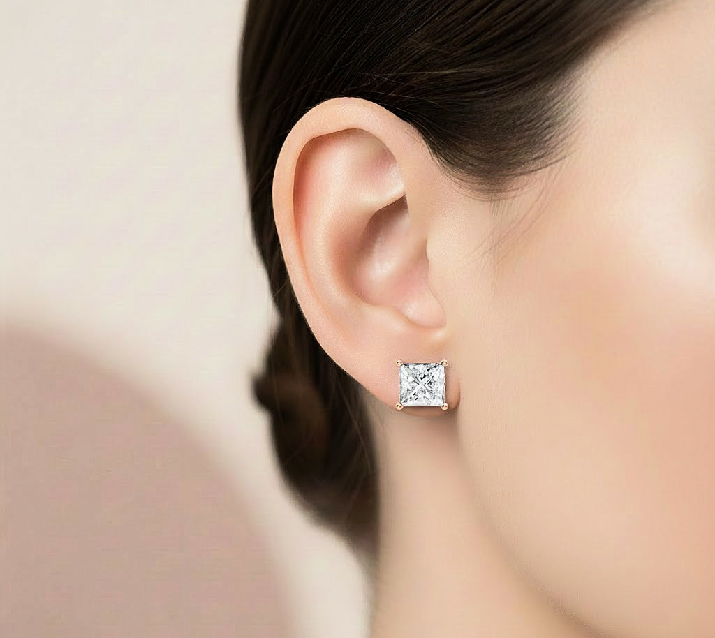 Princess cut diamond stud earrings worn on ear with white gold finish